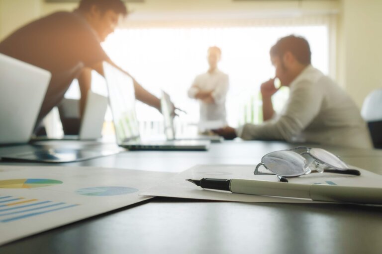 business-concept-with-copy-space-office-desk-table-with-pen-focus-analysis-chart-computer-notebook-cup-coffee-desk-vintage-tone-retro-filter-selective-focus - FranConnect Franchise development leader reviewing lead conversion and pipeline data