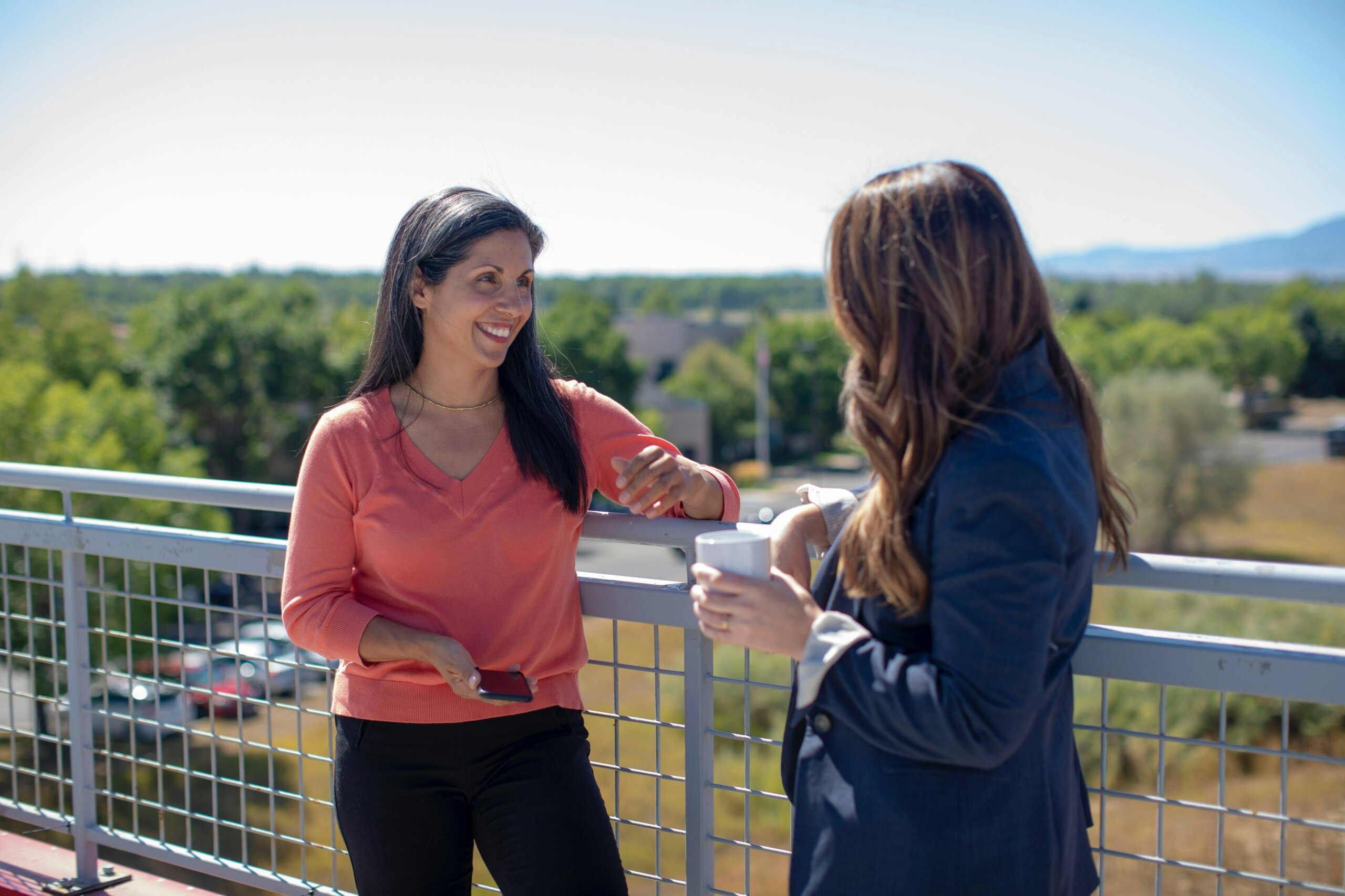 Two business women discuss out on a balcony