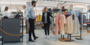 A retail employee approaches a woman looking at clothing
